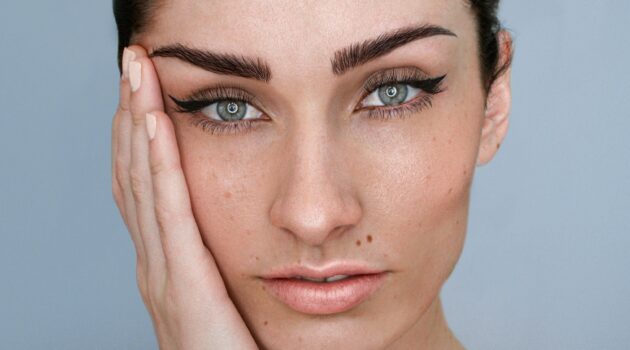 Gros plan sur le visage d’une femme avec un microblading des sourcils, un maquillage naturel et les cheveux bruns attachés