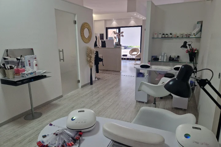 Accueil et espace manucure chez Estetica Francesca à Olbia, avec miroir rond et étagères vitrées de produits de beauté.