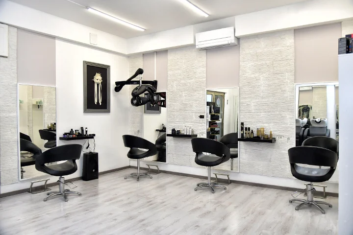 Postes de coiffage modernes chez Sp Beauty di Serena Pinna, près des plages de Pittulongu à Olbia, avec fauteuils noirs et grands miroirs.