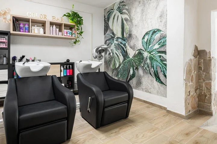 Bacs à shampoing et color bar au salon Yourself à Tortolì, avec une fresque murale monstera aux tons tropicaux.