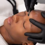 Gros plan d'une esthéticienne réalisant un dermaplaning sur une cliente en institut